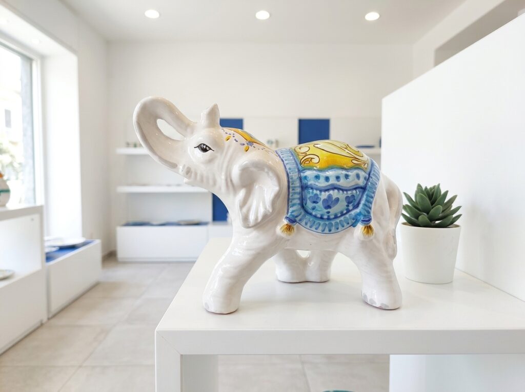 Elefante portafortuna in ceramica decorata esposto su una mensola bianca