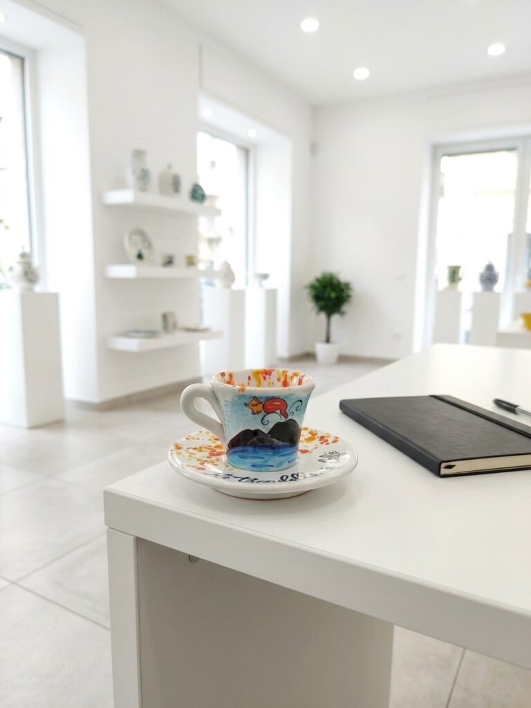 Set tazzine caffè in ceramica con decoro Vesuvio e cornetto portafortuna su una scrivania bianca